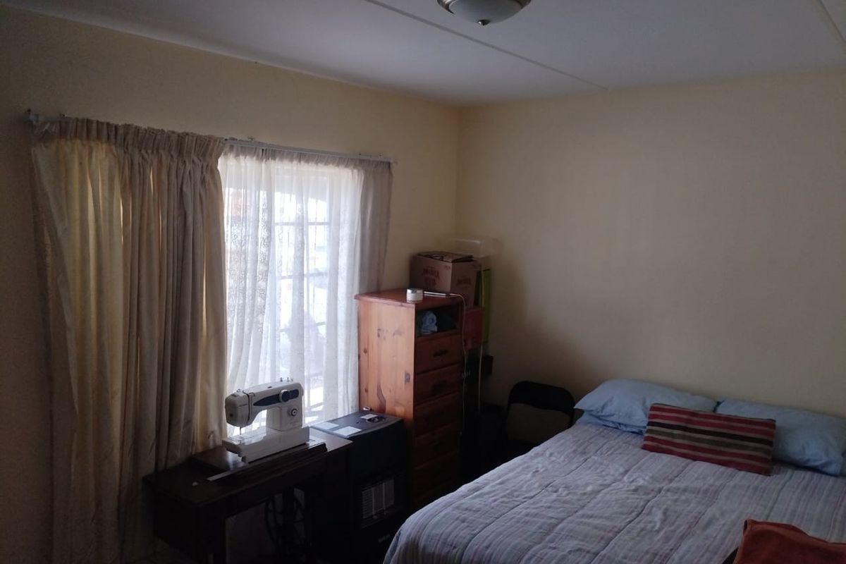 A functional bedroom featuring a sliding glass door providing natural light and a standard ceiling light fixture.