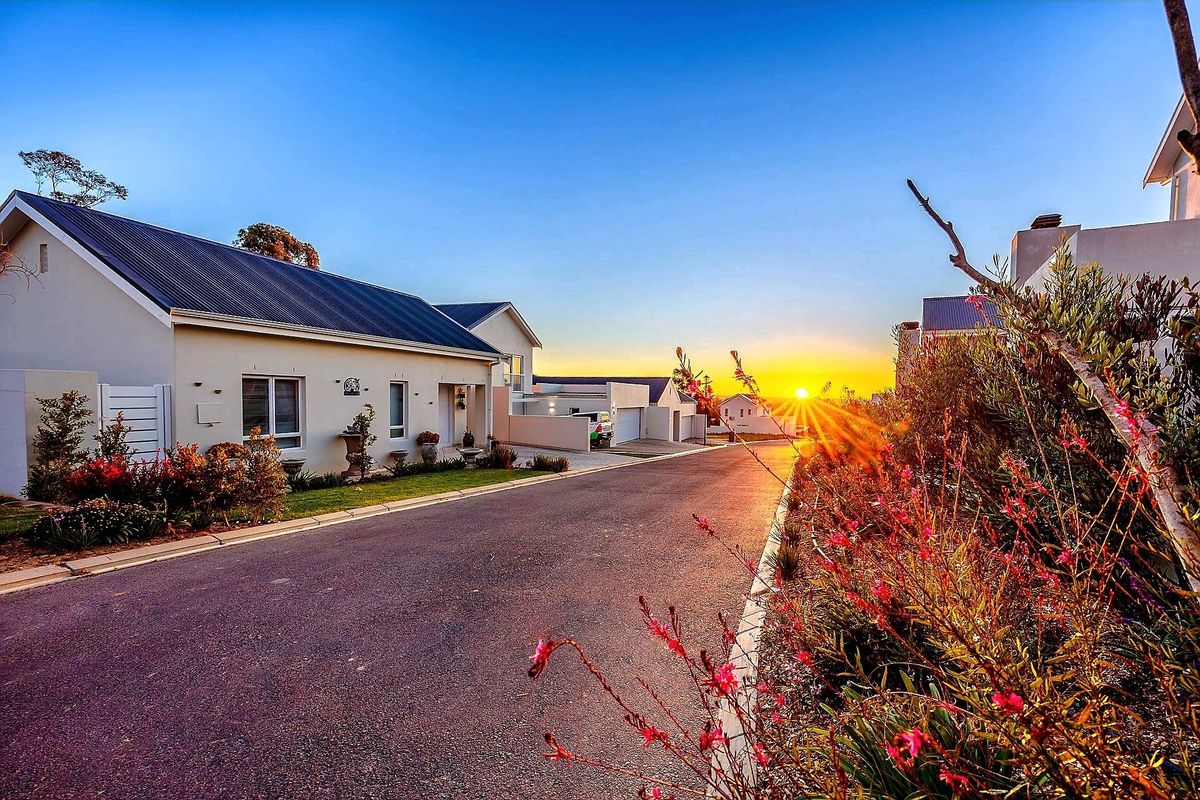 A scenic street view of a residential estate at sunset, featuring well-maintained homes with modern architectural finishes and landscaped surroundings.