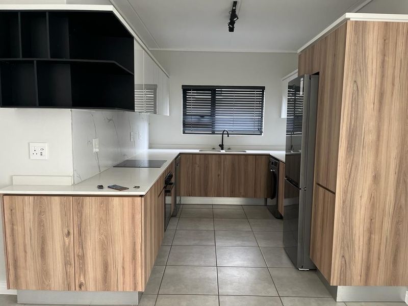 Modern kitchen featuring wood-grain cabinetry, stone countertops, marble-look splashback, integrated appliances, and tiled flooring in a clean, contemporary layout.