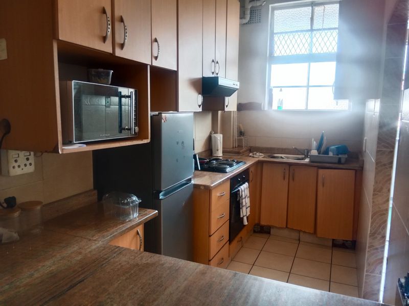 A functional kitchen featuring laminate cabinetry, built-in oven, hob, extractor fan, and tiled finishes, offering a practical layout for daily meal preparation.