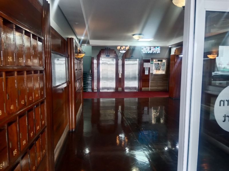 A well-maintained apartment building lobby featuring wood-paneled walls, integrated mailboxes, and dual elevators.