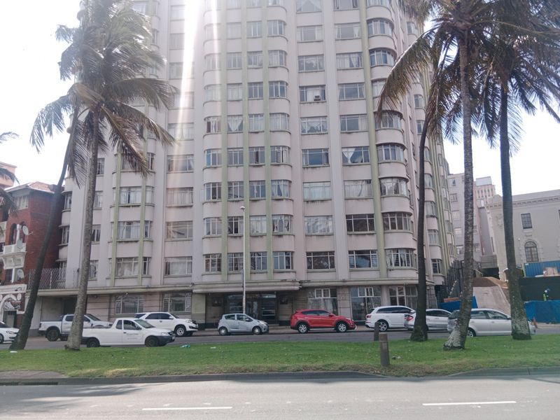 Front elevation of a multi-story apartment building featuring a classic architectural facade with extensive window banks and ground-level access.