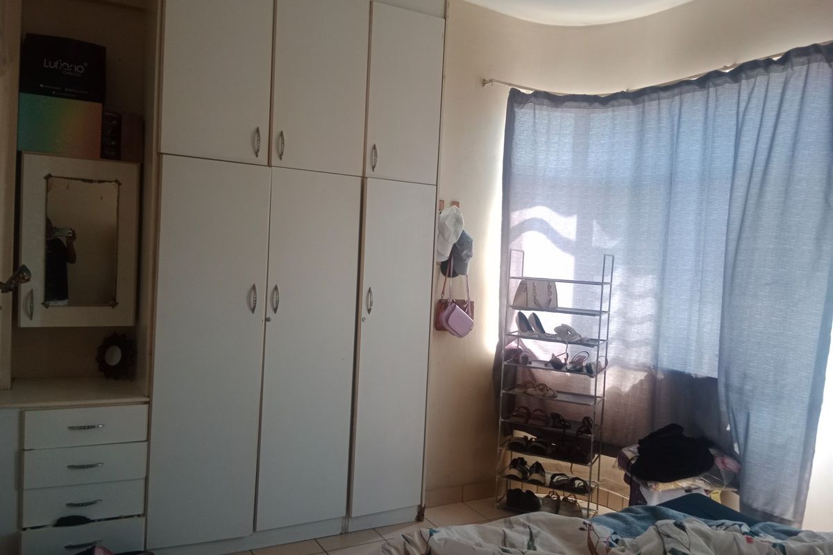Bedroom featuring a large white built-in wardrobe with integrated vanity and tiled flooring.