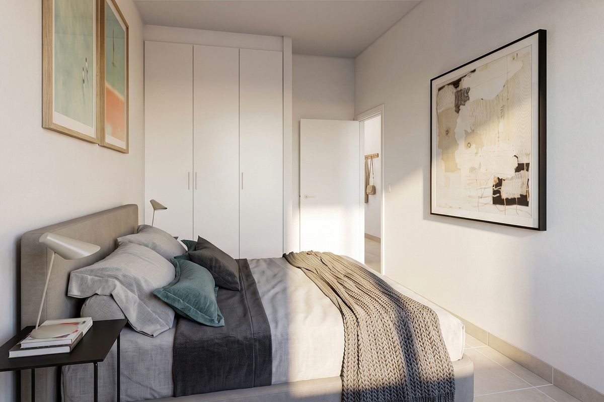 A modern, well-lit bedroom featuring built-in cupboards and neutral tiled flooring, presenting a clean and contemporary aesthetic.