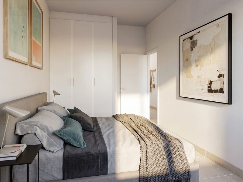 A modern, well-lit bedroom featuring built-in cupboards and neutral tiled flooring, presenting a clean and contemporary aesthetic.