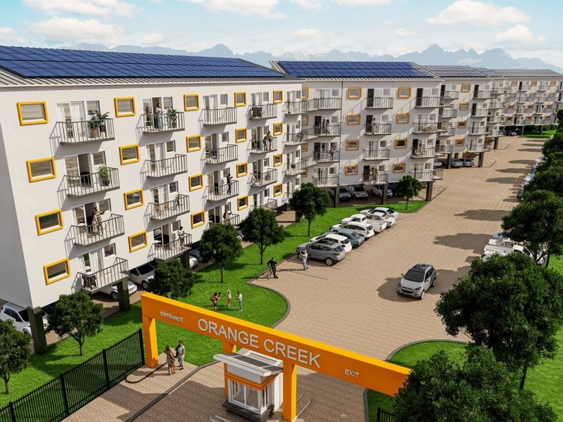 A modern residential apartment complex featuring solar panels, private balconies, a secure gated entrance, and landscaped grounds with paved parking areas.