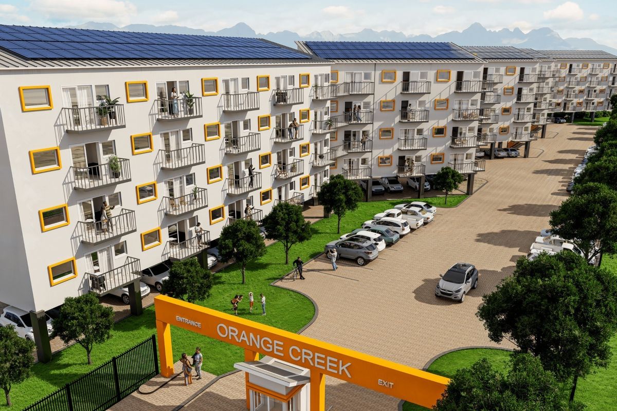 A modern residential apartment complex featuring solar panels, private balconies, a secure gated entrance, and landscaped grounds with paved parking areas.