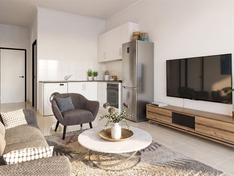 A modern open-plan living area featuring a compact kitchen with built-in cabinetry, oven, and sink, seamlessly integrated with a comfortable lounge space.