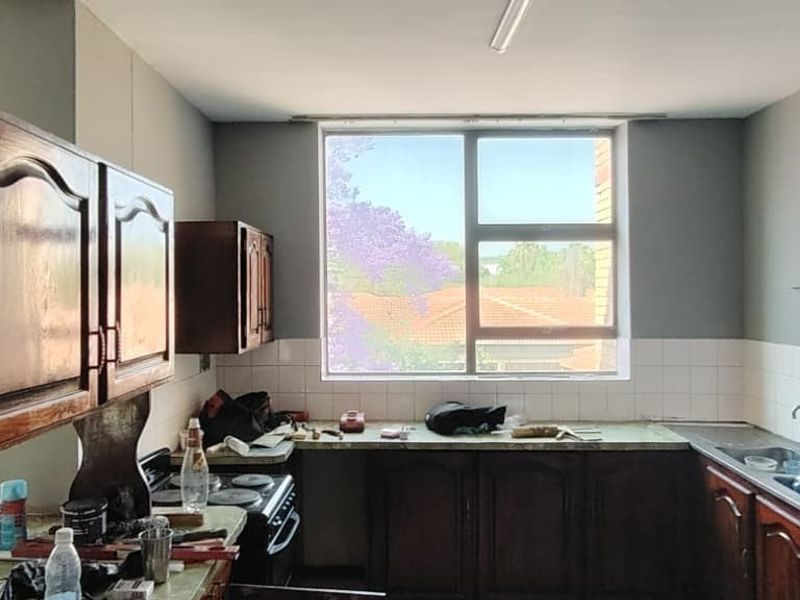 A dated kitchen featuring traditional wooden cabinetry, a tiled backsplash, and a large window providing natural light, ready for a modern renovation.