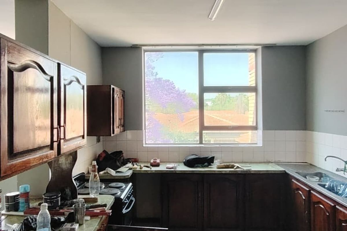 A dated kitchen featuring traditional wooden cabinetry, a tiled backsplash, and a large window providing natural light, ready for a modern renovation.