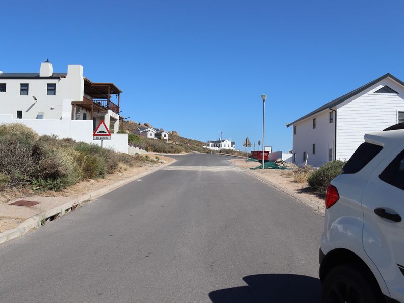 A clear street view showing the paved road, surrounding residential properties, and street infrastructure in a coastal residential area.