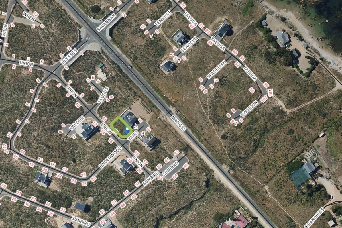 An aerial view of a residential land plot within a coastal neighborhood, showing surrounding street layout and nearby properties.