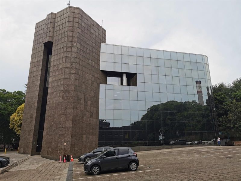 Modern commercial building featuring a striking combination of granite cladding and a reflective glass curtain wall facade with adjacent paved parking.