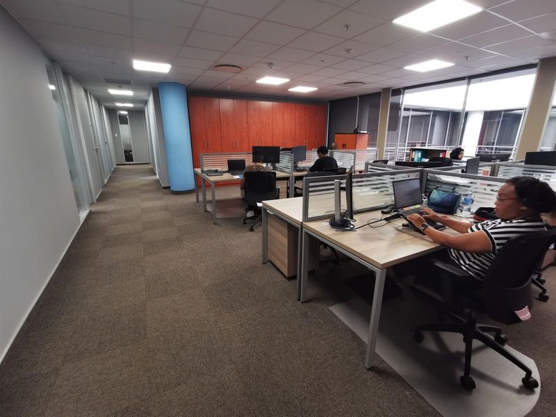 A modern open-plan commercial office space featuring carpeted flooring, suspended ceilings with recessed lighting, and integrated storage cabinetry.