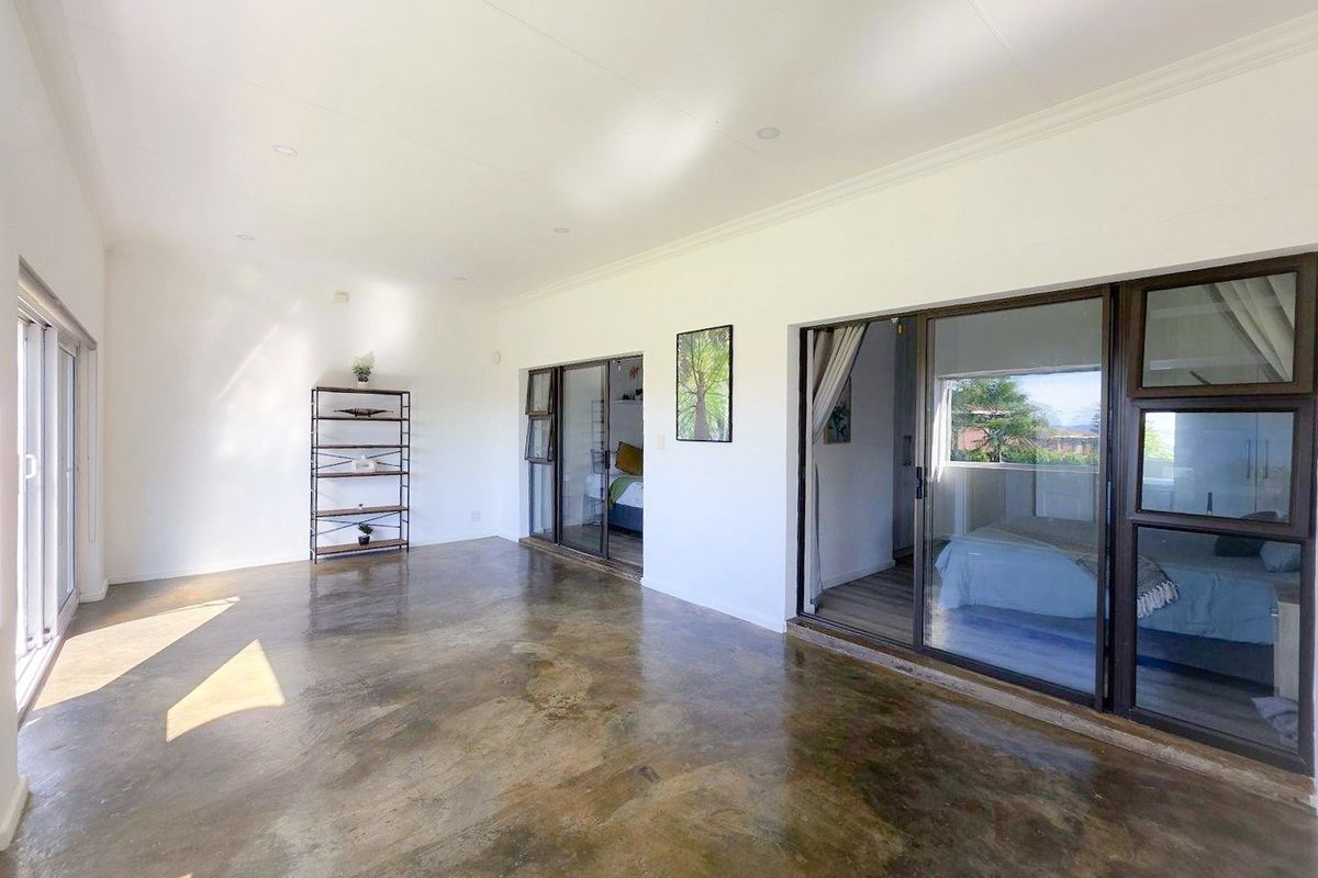 Spacious living area featuring polished concrete floors, recessed lighting, and large sliding glass doors providing access to adjacent rooms.