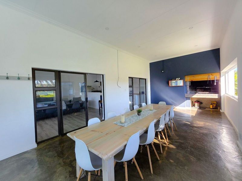 Spacious open-plan living and dining area featuring polished concrete floors, large sliding glass doors, and a built-in indoor braai fireplace.
