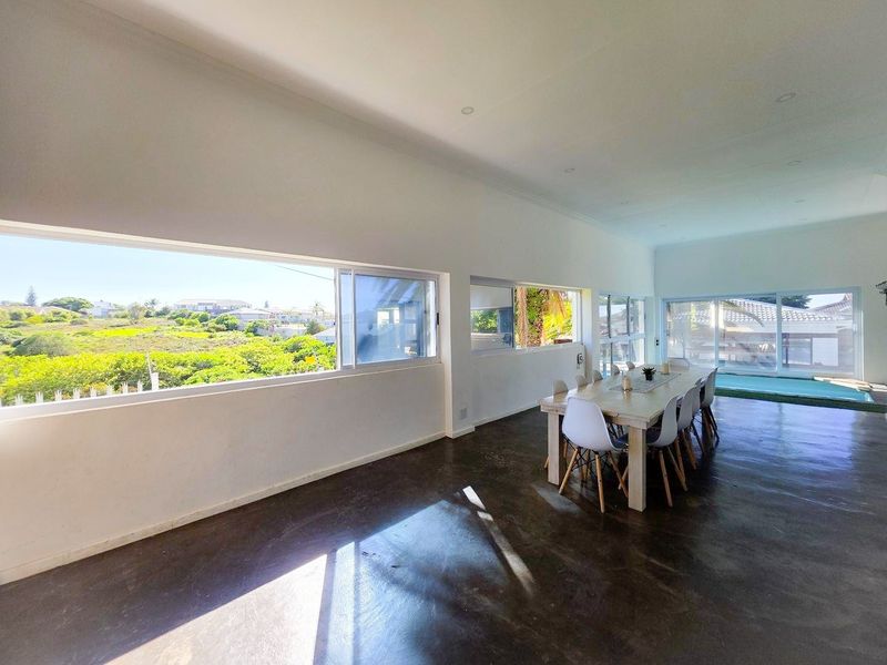 Spacious open-plan living and dining area featuring polished concrete floors, expansive windows with scenic views, and direct access to outdoor space.