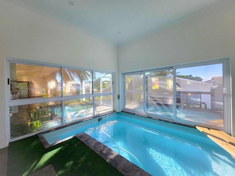 A bright indoor swimming pool area featuring large sliding glass doors that provide natural light and views of the outdoor surroundings.