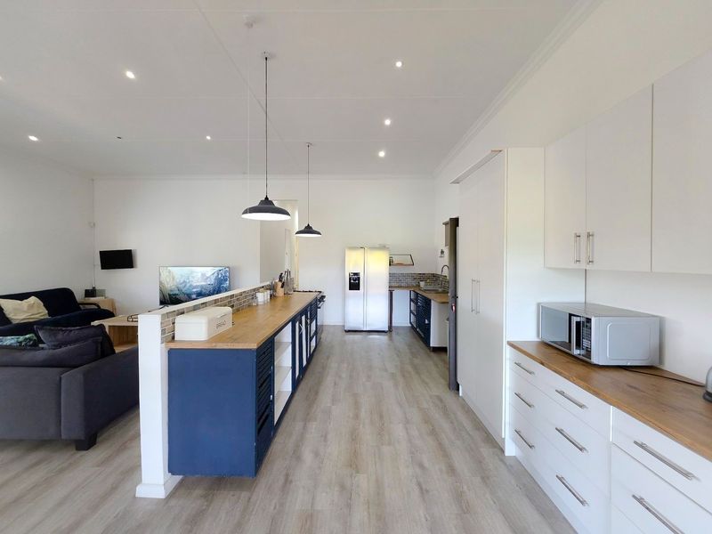 Spacious open-plan kitchen and living area featuring modern cabinetry, a central island with wood countertop, and contemporary recessed lighting.