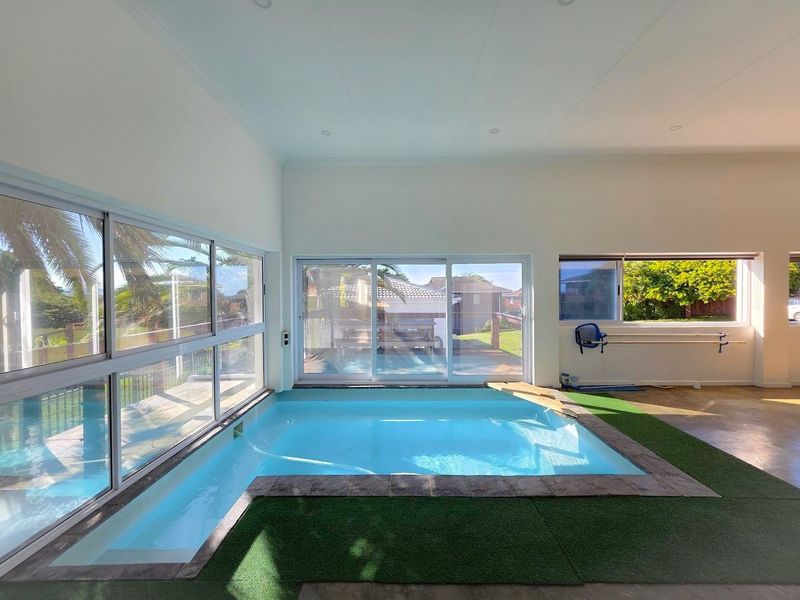 An indoor swimming pool area featuring large sliding glass doors, tiled surrounds, and recessed lighting, offering a bright and versatile space.