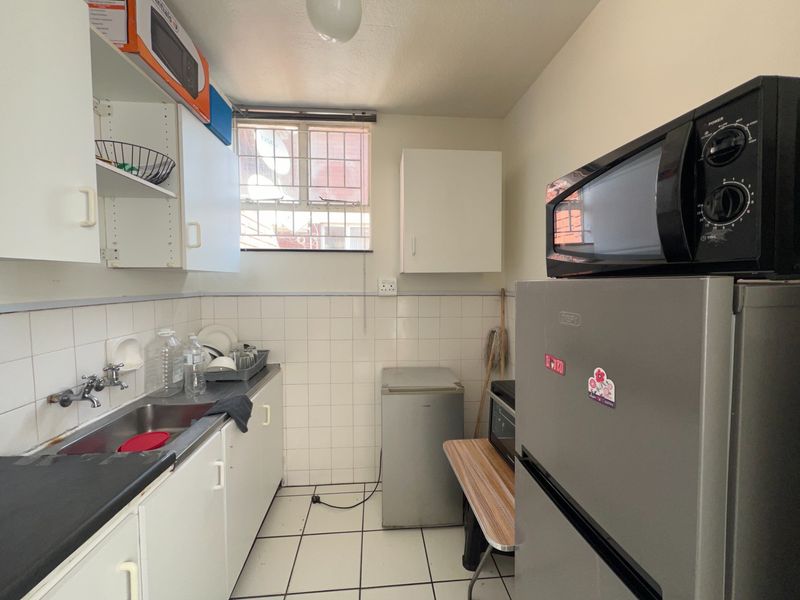 A functional scullery area featuring built-in cabinetry, a stainless steel sink, and tiled finishes, providing additional utility and storage space.