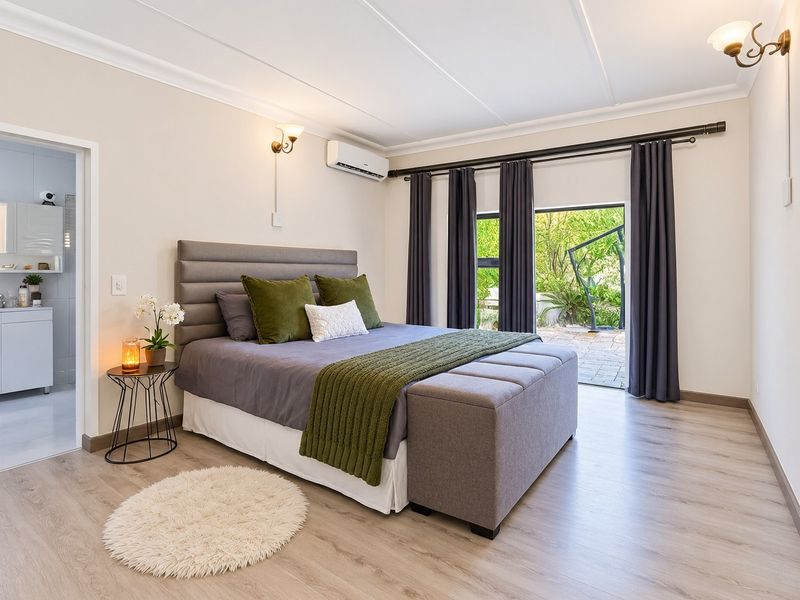 Spacious bedroom featuring laminate flooring, air conditioning, and direct access to a private patio through sliding glass doors.