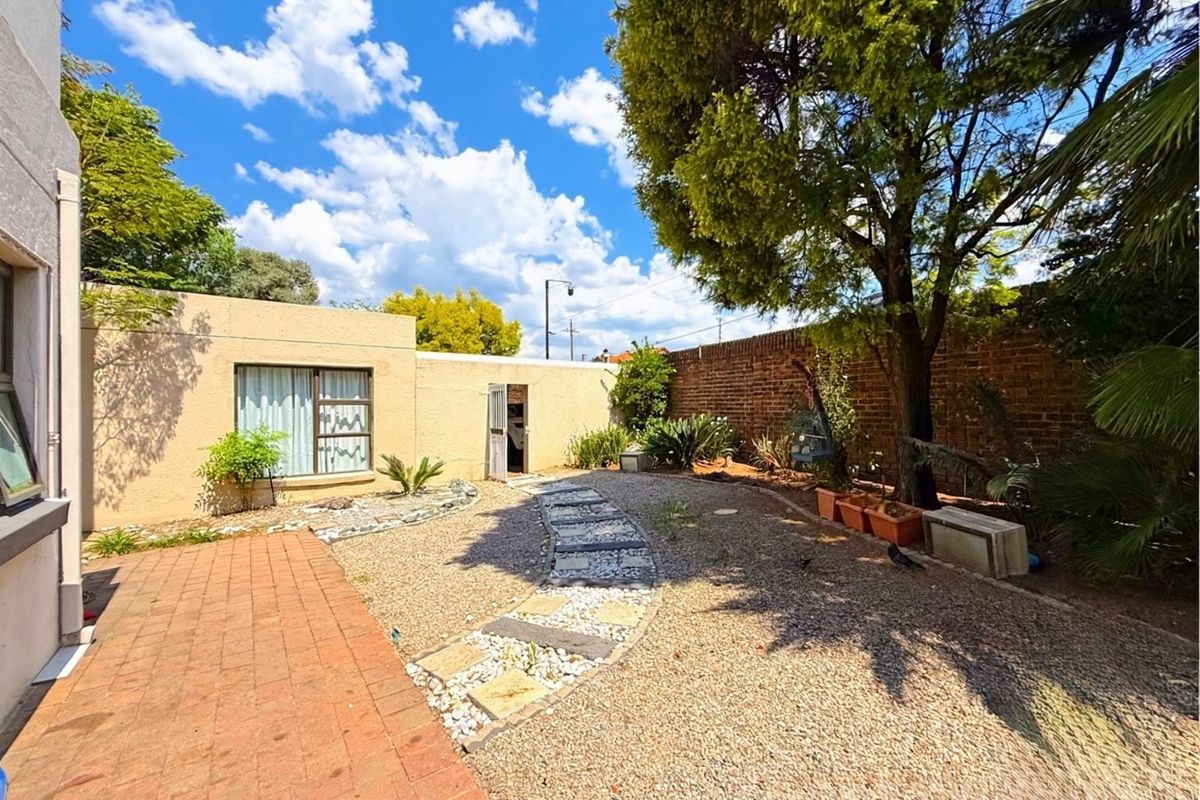 A private rear garden area featuring a paved walkway, gravel landscaping, and a brick boundary wall, providing a low-maintenance outdoor space.
