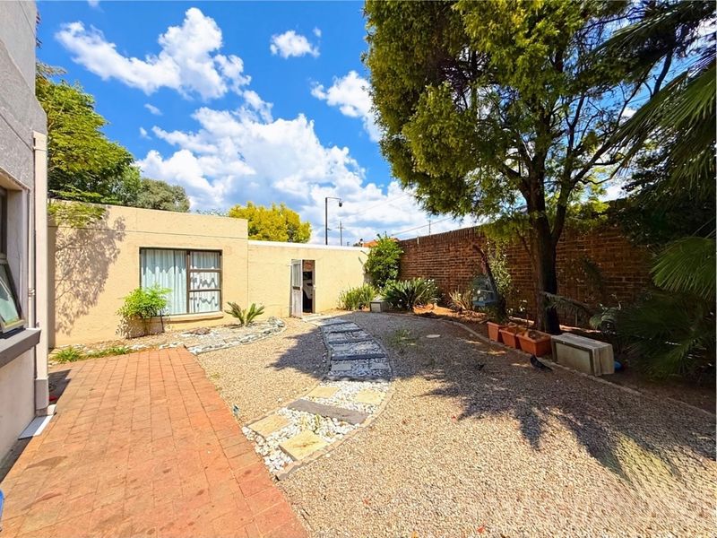 A private rear garden area featuring a paved walkway, gravel landscaping, and a brick boundary wall, providing a low-maintenance outdoor space.
