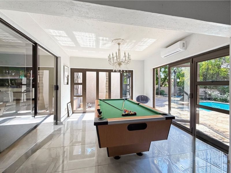 Bright living area featuring large sliding glass doors, polished tile flooring, and a split-system air conditioner, offering direct access to the pool area.