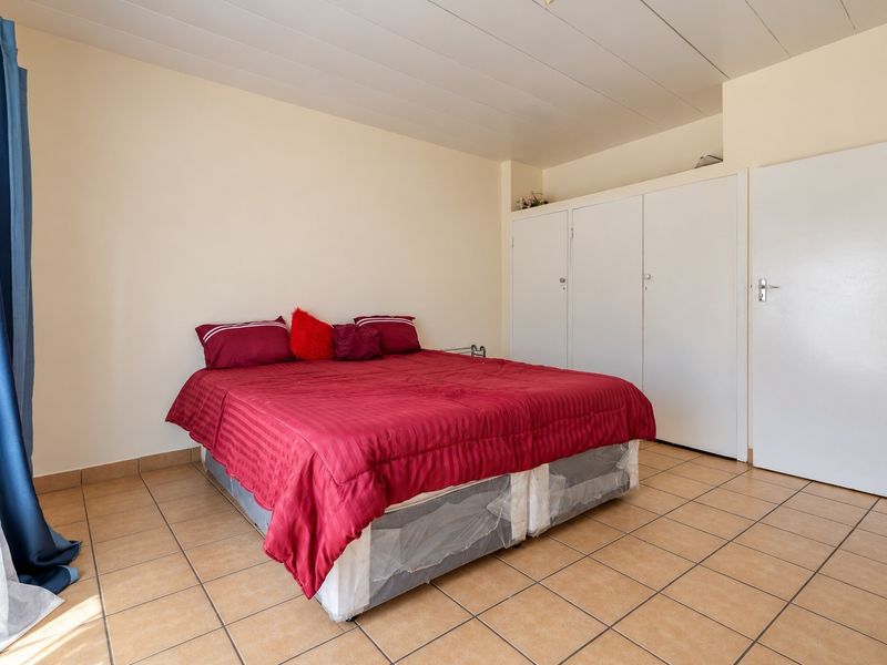 A bedroom featuring tiled flooring, a panelled ceiling, and built-in cupboards providing ample storage space.