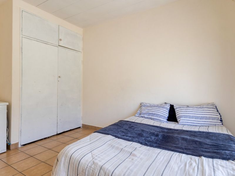 A bedroom featuring tiled flooring and a built-in wardrobe with painted doors.