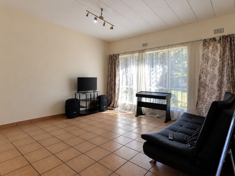 Spacious living room featuring neutral walls, tiled flooring, and large sliding glass doors that provide ample natural light.