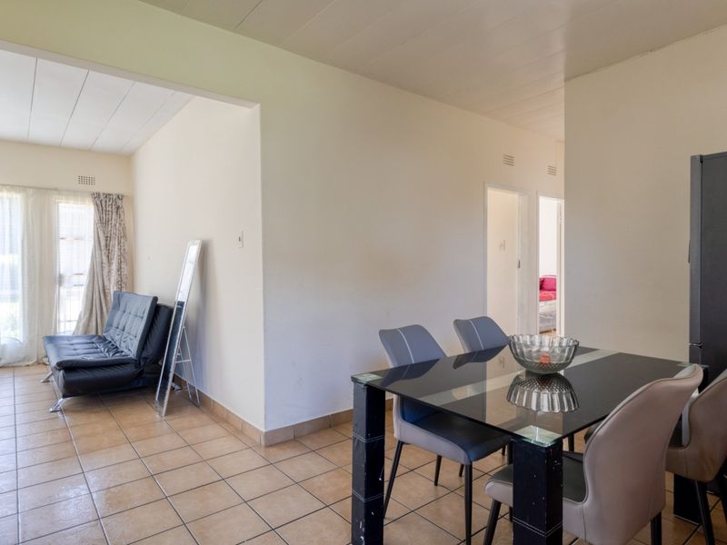 Open plan living and dining area featuring tiled flooring, a panelled ceiling, and access to a patio through a sliding glass door.