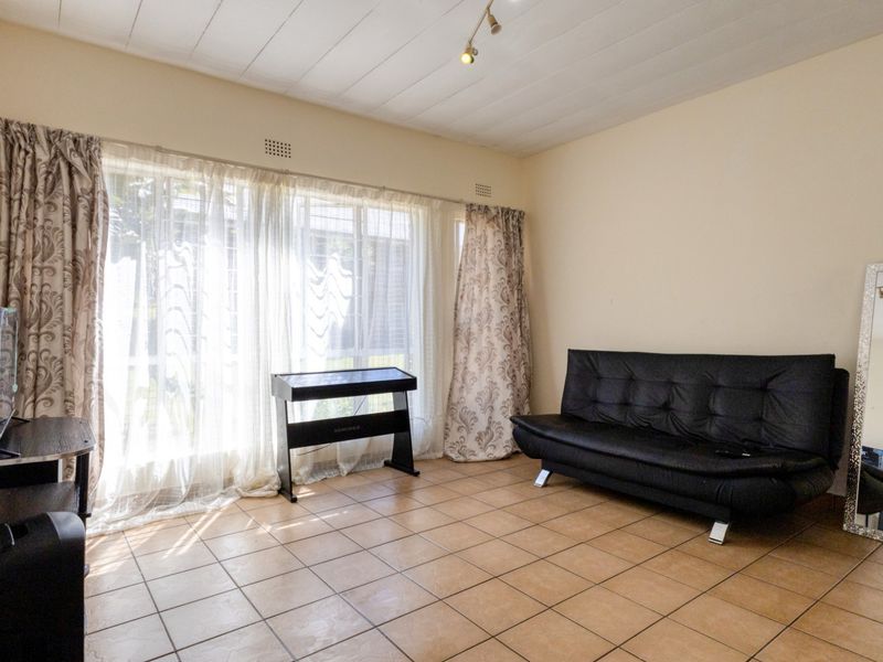 A living room featuring tiled flooring and a large window that allows for ample natural light.