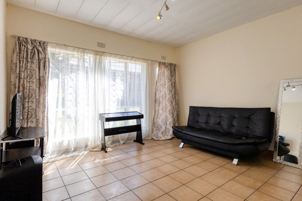 A living room featuring tiled flooring and a large window that allows for ample natural light.