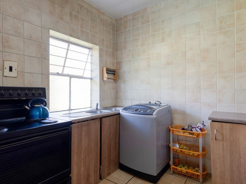 A functional kitchen featuring built-in cabinetry, a stainless steel sink, and tiled wall finishes, providing a practical space for daily meal preparation.