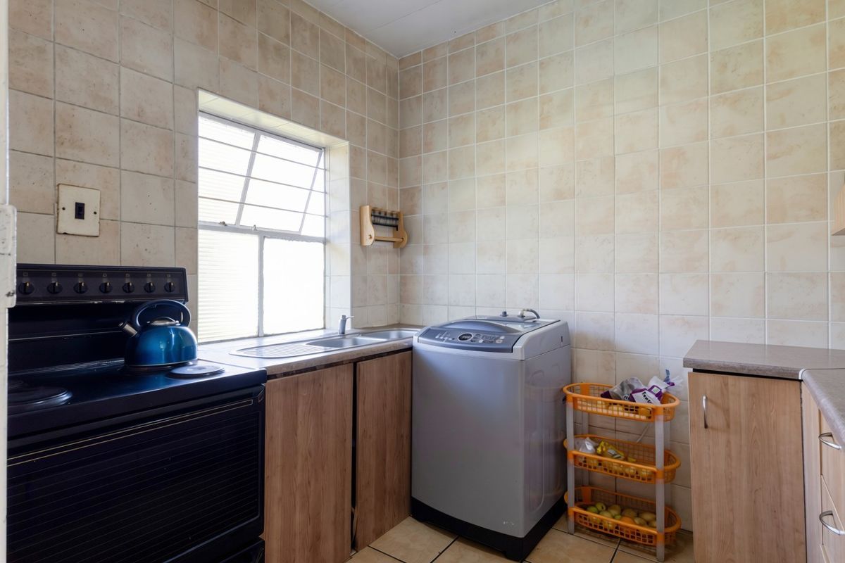 A functional kitchen featuring built-in cabinetry, a stainless steel sink, and tiled wall finishes, providing a practical space for daily meal preparation.