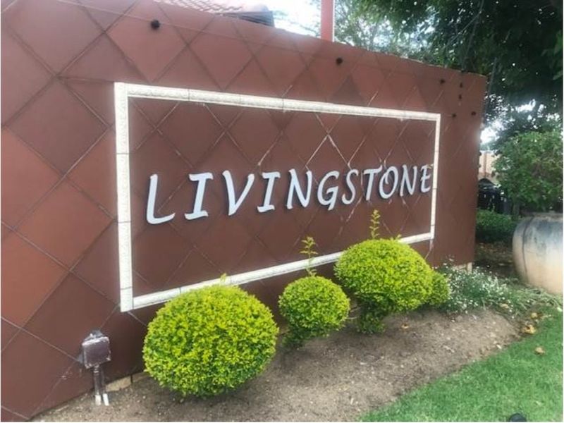 The entrance signage for the Livingstone apartment complex, featuring a decorative wall and manicured garden beds.
