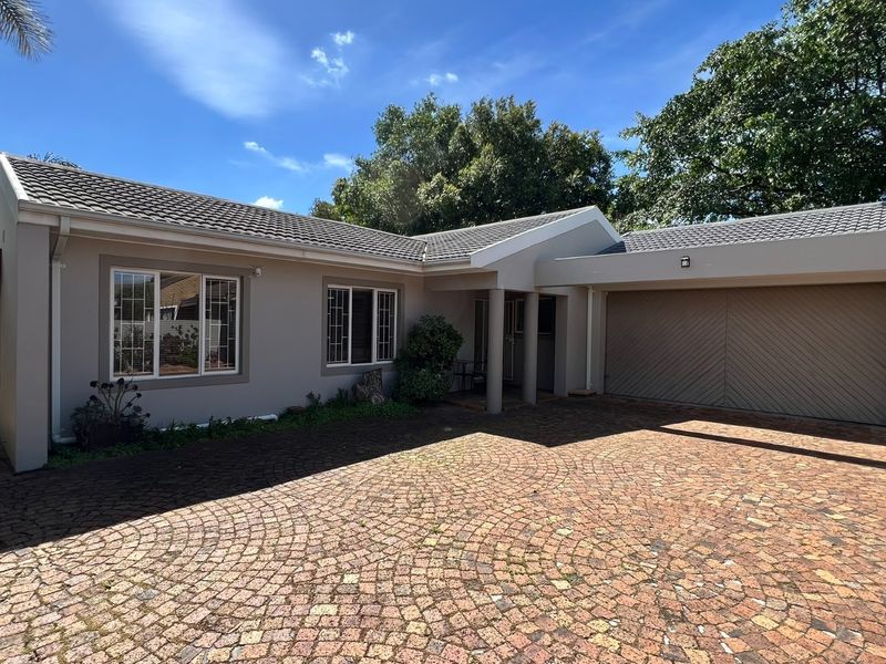 Front elevation of a well-maintained house featuring a paved driveway, integrated garage, and tiled roof.