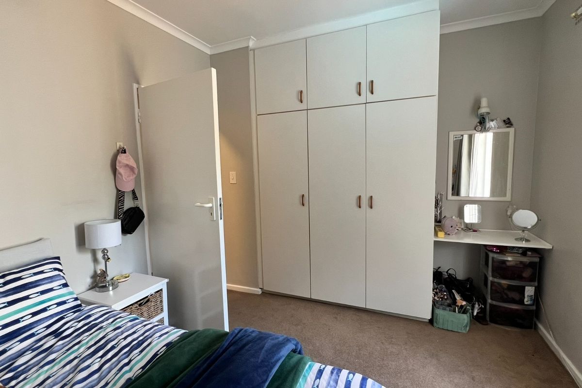 A well-maintained bedroom featuring ample built-in cupboard storage and a dedicated vanity area with a fitted shelf.