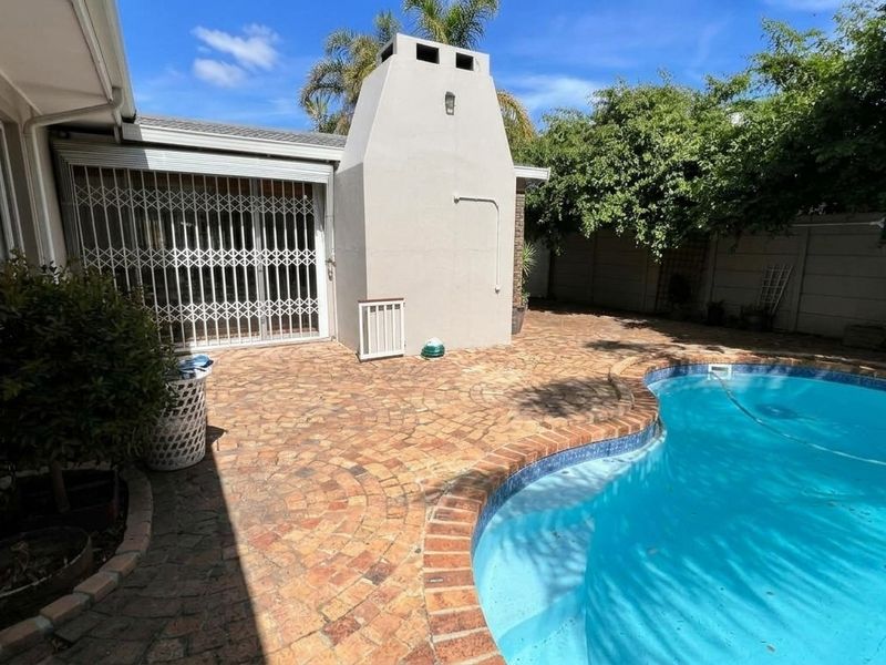 Outdoor pool area featuring a brick-paved patio, a built-in fireplace, and a swimming pool, perfect for entertaining.