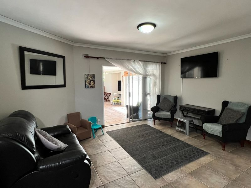A functional living room featuring tiled flooring and a sliding glass door that provides access to an outdoor patio area.