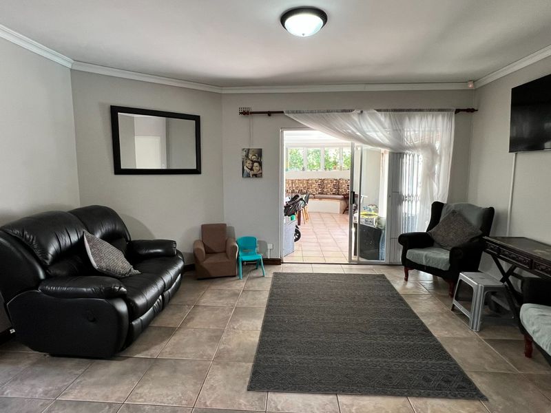 Spacious living room featuring neutral wall tones, tiled flooring, and a sliding glass door providing direct access to the outdoor patio area.