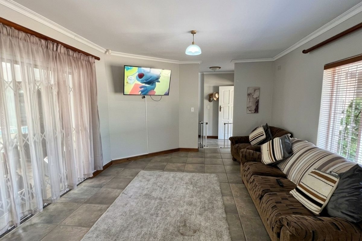 A spacious living room featuring tiled flooring, neutral wall tones, and a sliding glass door providing access to the exterior.