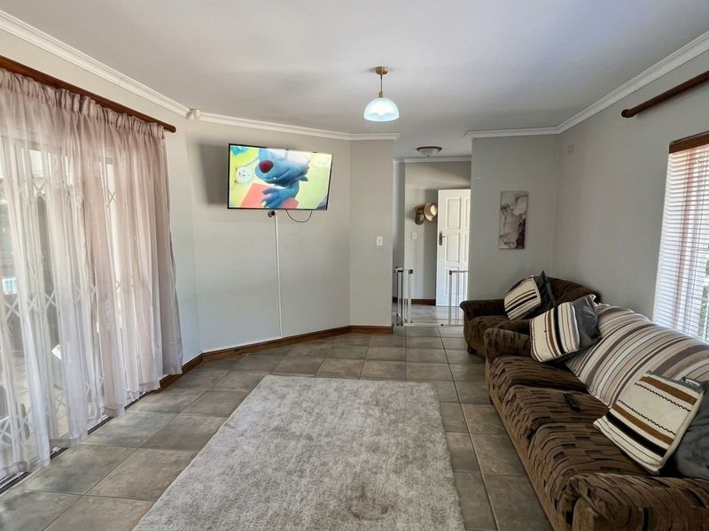 A spacious living room featuring tiled flooring, neutral wall tones, and a sliding glass door providing access to the exterior.