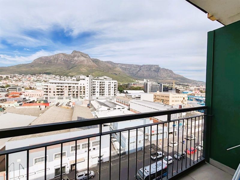 An elevated balcony view overlooking the urban cityscape with a prominent mountain backdrop.