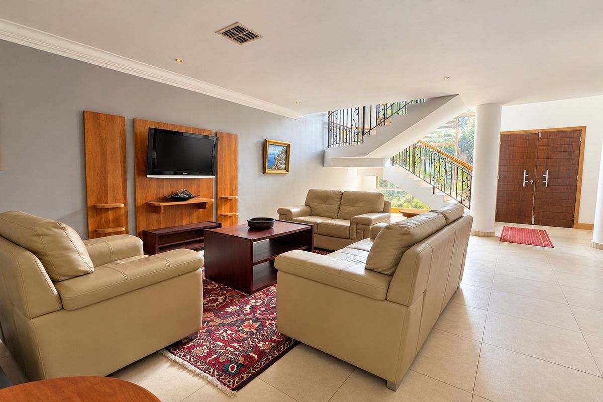 Spacious living area featuring tiled flooring, recessed lighting, and a prominent staircase with a decorative wrought iron balustrade leading to the upper level.