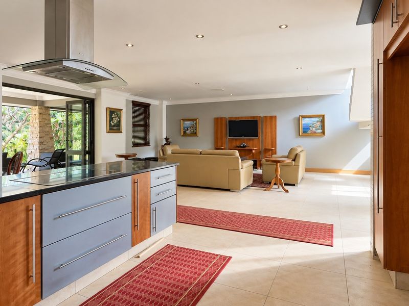 Spacious open-plan living area featuring a modern kitchen with a central island, sleek cabinetry, and seamless flow to an outdoor patio through sliding doors.