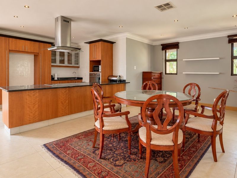 Spacious open-plan kitchen and dining area featuring wooden cabinetry, a central island with a breakfast bar, and modern recessed lighting throughout.