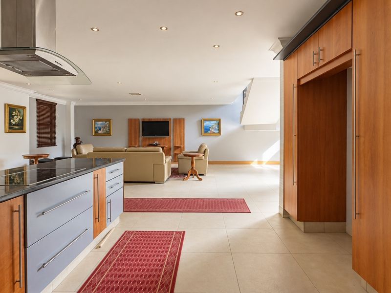 Spacious open-plan living area featuring a modern kitchen with a central island, sleek cabinetry, and seamless flow to the lounge and outdoor access.